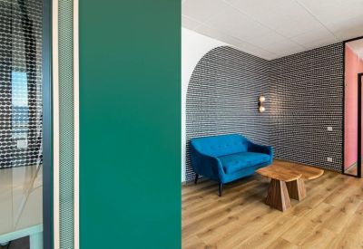 Modern reception lounge with a blue velvet sofa, a wooden coffee table, and an arched feature wall.