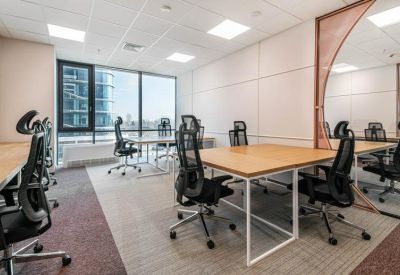 Bright open-plan office with multiple workstations, ergonomic black chairs, and large windows.