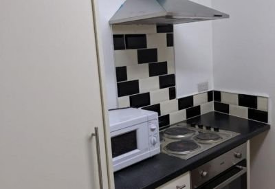 Modern compact kitchen with black and white tiled backsplash and blue extractor hood.