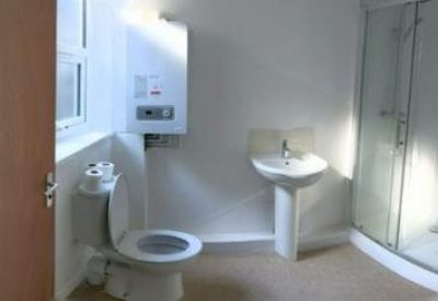 Bright white bathroom featuring a walk-in glass shower and pedestal sink.