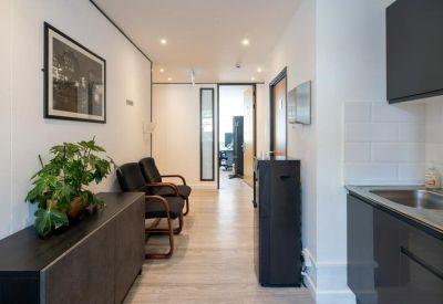 Communal kitchenette area and breakout space with comfortable black armchairs.