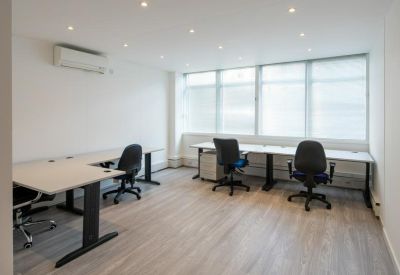 Bright four-person office suite with L-shaped desks and ergonomic chairs.