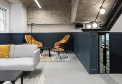 Cozy breakout nook with teal wall paneling and two orange lounge chairs.