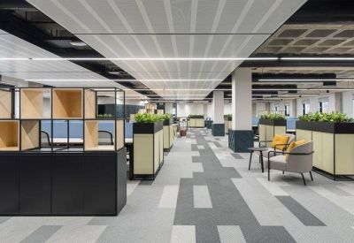 Open-plan workspace with modular wooden shelving and green planters.
