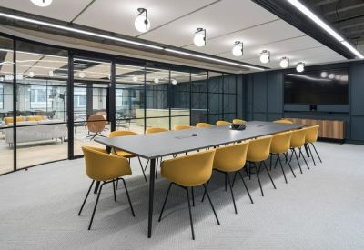 Large boardroom featuring a long grey table, yellow chairs, and glass partition walls.