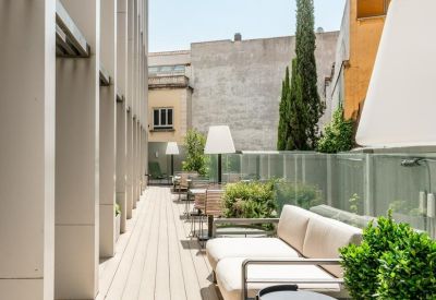 Sunny rooftop terrace with wood decking and modern white outdoor sofas.