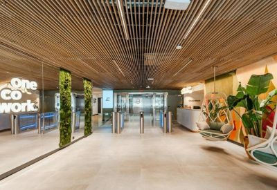 Modern reception area with turnstile entry, wooden slat ceiling, and hanging chairs.