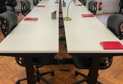 Two rows of white sit-stand desks with black ergonomic chairs.