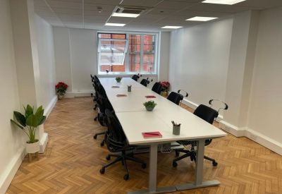 Long white boardroom table in a bright meeting room with wood floors.