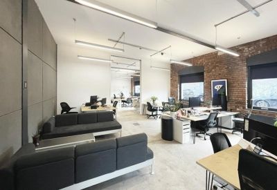 Spacious communal lounge with dark grey sofas and an industrial exposed brick wall.