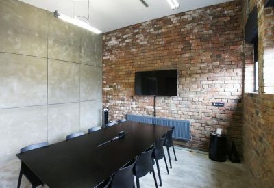 Meeting room with a long black table, modern chairs, and a large wall-mounted screen.