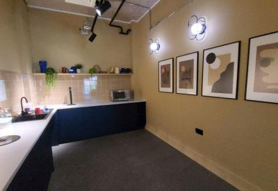 Sleek kitchenette with dark cabinetry, integrated appliances, and contemporary wall art.