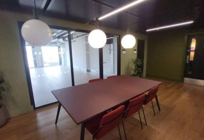 Meeting room with a large dark wood table, red chairs, and globe pendant lighting.