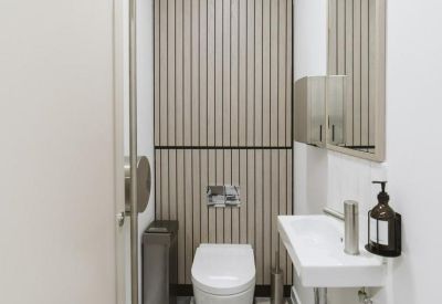 Sleek restroom stall featuring a wall-hung toilet and monochromatic geometric floor tiles.
