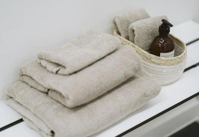 Close-up of folded beige towels and a soap dispenser on a white slatted bench.