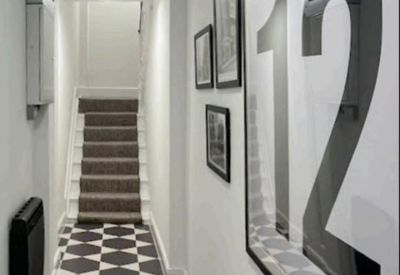 Narrow hallway featuring monochrome hexagonal floor tiles and framed wall art.