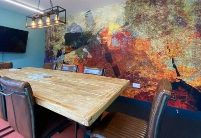 Meeting room with a large wooden table, leather chairs, and a colorful abstract mural.