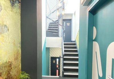 Corridor featuring a staircase with blue accents and a door marked for restroom facilities.