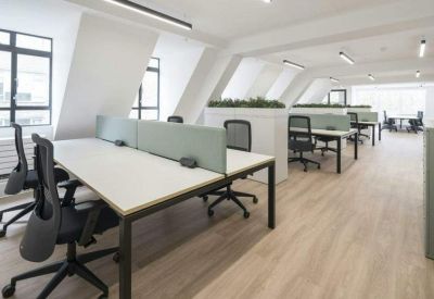 Rows of white desks with black ergonomic chairs in a bright, minimalist office space.