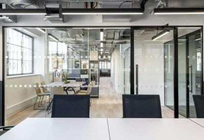 Modern meeting room with a long white table and glass walls showing the office interior.