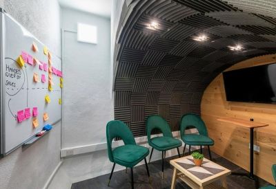 Meeting pod with soundproofed arched ceiling and teal velvet chairs.