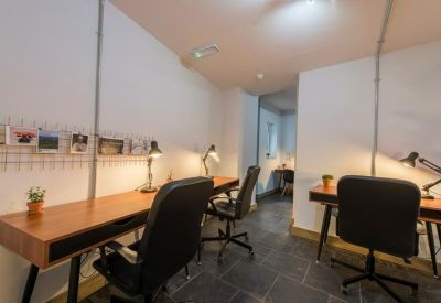 Close-up of two black adjustable desk lamps on wooden office tables.
