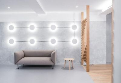 Bright reception or waiting area with a grey sofa and unique circular wall lighting displays.