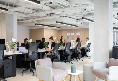 Open-plan workspace with multiple desks, ergonomic chairs, and industrial-style ceiling.