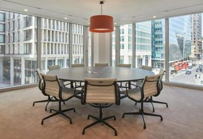 Meeting room with a round table and grey chairs featuring city views through floor-to-ceiling windows.