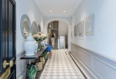 Reception hallway featuring checkered flooring, ornate mirrors, and white decorative vases.