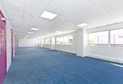 Spacious open-plan office with blue carpeting and vibrant purple doors.