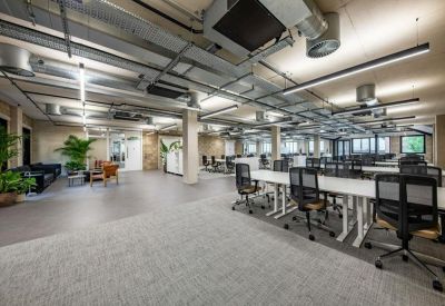 Expansive open office area with white bench desking and grey carpeting.