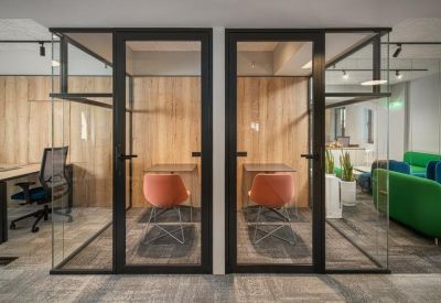 Two private glass-enclosed phone booths with orange chairs and wood-textured back walls.