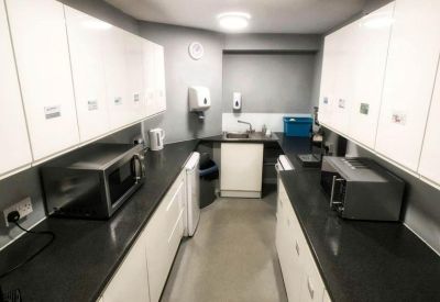Narrow galley kitchen with white cabinetry and dark countertops.
