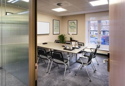 Professional meeting room with a large table, black mesh chairs, and framed maps.