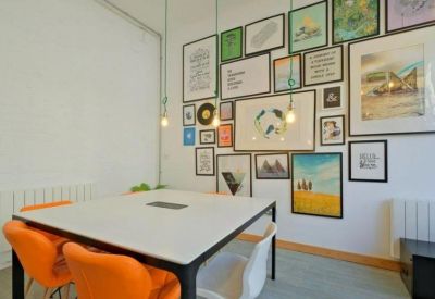 Bright meeting room featuring a gallery wall of framed art and vibrant orange chairs.