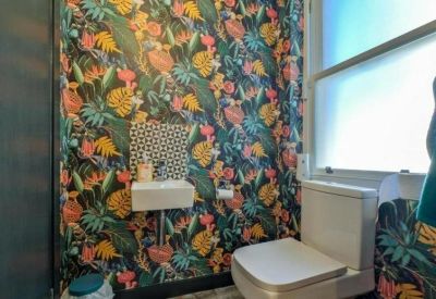 Small restroom featuring vibrant tropical leaf patterned wallpaper and a white wall-mounted sink.