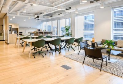 Spacious communal coworking area with green chairs and wooden floors.