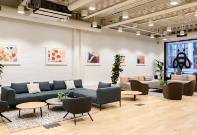 Reception lounge with a large blue corner sofa and colorful abstract paintings.