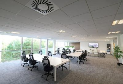 Bright open-plan workspace featuring white desks and black mesh ergonomic chairs.
