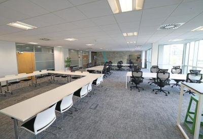 Large modular meeting room with tables arranged in a U-shape and bright windows.