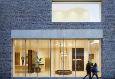 Modern lobby entrance with a unique circular wooden bench and tall glass windows.