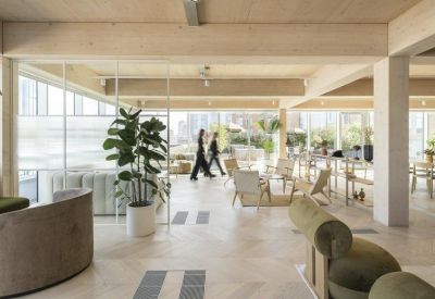 Expansive open-plan office with exposed wood beams and indoor plants.