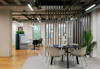 Open-plan office area with a round meeting table separated by a vertical timber slat screen.