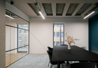 Minimalist meeting room with a black table, grey carpet, and industrial-style ceiling.