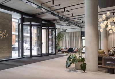 Modern reception lobby with revolving doors, concrete pillars, and designer globe lighting.