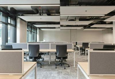 Open-plan office with grey workstations and industrial ceiling finish.