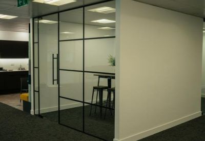 Meeting room with a large table and industrial-style black framed glass partitions.