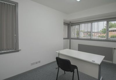 Compact individual office workspace with grey carpet and window blinds.