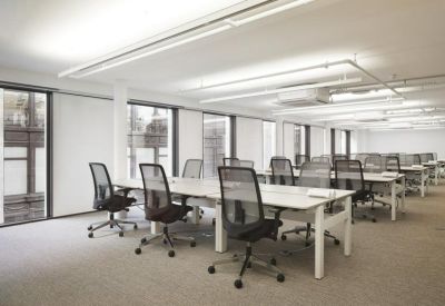 Large open-plan office with rows of white desks and ergonomic mesh chairs.